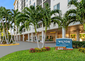 Thumbnail 22 of 22 - Exterior view of Wilton Tower apartments with palm trees in Wilton Manors, FL.