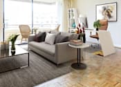 Thumbnail 44 of 66 - A living room with a grey couch, a coffee table, a chair, a potted plant, a bookshelf, and a painting on the wall.
