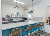 Thumbnail 13 of 35 - 1-Bedroom Apartments in Everett, Washington - Woodbrook - Community Kitchen with Coffee Maker, Microwave, Breakfast Bar with Bar-Style Wicker Chairs, and Pendant Lights.