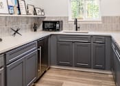 Thumbnail 14 of 35 - A kitchen with dark grey cabinets and a white countertop.
