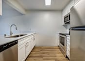 Thumbnail 3 of 35 - Apartments in Everett for Rent - Woodbrook - Kitchen with Wood-Style Flooring, White Countertops, White Cabinets, and Stainless Steel Appliances