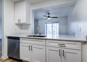 Thumbnail 1 of 35 - One-Bedroom Apartments in Everett, Washington - Woodbrook - Kitchen with Wood-Style Flooring, Stainless Steel Dishwasher, Sleek White Cabinets, and Breakfast Bar.