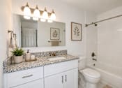 Thumbnail 7 of 23 - A bathroom with a marble countertop and white fixtures.