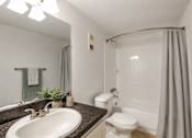 Thumbnail 11 of 23 - A bathroom with a white toilet, sink, and shower.