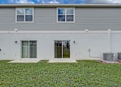 Thumbnail 2 of 36 - A house with a grey roof and white walls with a green lawn in front.