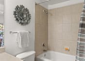 Thumbnail 14 of 30 - A bathroom with a white toilet, a white towel, and a white bathtub.