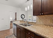 Thumbnail 8 of 30 - A kitchen with brown cabinets and granite countertops.