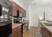 Thumbnail 5 of 30 - A kitchen with dark brown cabinets and a black refrigerator.
