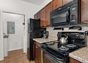 Thumbnail 9 of 30 - A black microwave oven is mounted above a black stove.