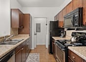 Thumbnail 10 of 30 - A kitchen with black appliances and wooden cabinets.
