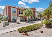 Thumbnail 25 of 30 - A red and beige apartment building with a landscaped front yard.