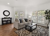 Thumbnail 3 of 30 - A living room with a grey couch, a coffee table, and a mirror on the wall.