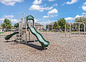 Thumbnail 23 of 30 - A playground with a green slide and a metal structure.