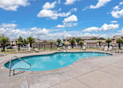Thumbnail 21 of 30 - A swimming pool surrounded by a concrete patio and a metal fence.