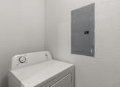 Thumbnail 17 of 30 - A white washing machine sits next to a wall-mounted electrical panel.