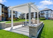 Thumbnail 20 of 28 - a pergola with a picnic table in front of an apartment complex