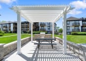 Thumbnail 22 of 28 - a picnic table under a white pergola in front of an apartment building