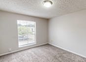 Thumbnail 14 of 28 - A room with a carpeted floor and a window overlooking a parking lot.