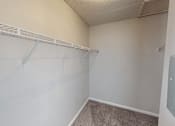 Thumbnail 15 of 28 - Empty room with a white wall and a grey carpet.