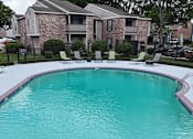 Thumbnail 24 of 28 - A swimming pool in front of a brick apartment building.