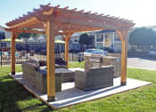 Thumbnail 3 of 13 - a patio with a seating area and a wooden pergola with grill station