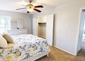 Thumbnail 10 of 32 - A bedroom with a bed, dresser, and a ceiling fan.
