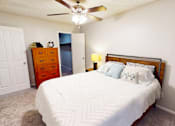 Thumbnail 12 of 32 - A bedroom with a bed, dresser, and ceiling fan.
