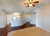 Thumbnail 5 of 24 - a living room with a ceiling fan and a kitchen in the background