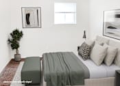 Thumbnail 5 of 32 - A bedroom with a bed, a bench, and a potted plant.