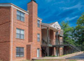 Thumbnail 19 of 22 - a brick apartment building with a balcony and a blue sky