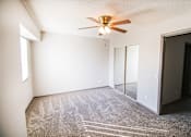 Thumbnail 6 of 23 - A room with a ceiling fan and carpeted floor.