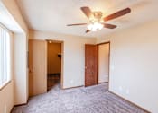 Thumbnail 7 of 23 - A room with a ceiling fan and carpeted floor.