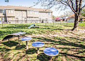 Thumbnail 12 of 23 - A playground with a blue table and a slide in the background.