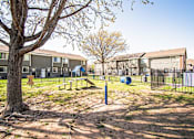 Thumbnail 13 of 23 - A playground area with a swing set and a slide in front of apartment buildings.
