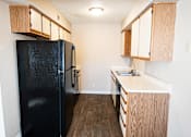 Thumbnail 1 of 23 - A black fridge in a kitchen with wooden cabinets.
