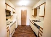 Thumbnail 2 of 23 - A kitchen with a white fridge, black stove, and wooden cabinets.