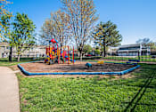 Thumbnail 11 of 23 - A playground with a blue rubberized surface and a red and yellow slide.