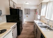 Thumbnail 2 of 21 - A kitchen with a black refrigerator and white countertops.