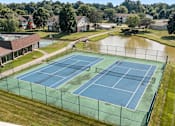 Thumbnail 18 of 22 - A tennis court with a green fence and a pond in the background.