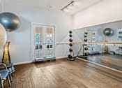 Thumbnail 12 of 22 - A room with a mirror, exercise balls, and a wooden floor.