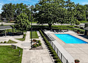 Thumbnail 39 of 41 - A pool surrounded by a concrete fence and green trees.