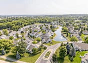 Thumbnail 15 of 16 - A bird's eye view of a residential neighborhood with houses, a pond, and a winding road.