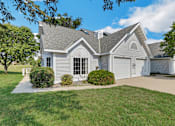 Thumbnail 9 of 16 - A house with a grey roof and white walls is surrounded by a well-kept lawn.