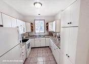 Thumbnail 1 of 16 - A kitchen with white cabinets and a tiled floor.