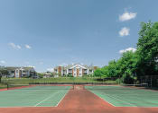 Thumbnail 20 of 26 - a tennis court with apartments in the background
