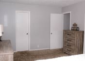 Thumbnail 11 of 17 - A room with two doors and a dresser with a lamp on top.