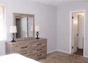 Thumbnail 10 of 17 - A bedroom with a bed, dresser, and mirror.