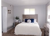 Thumbnail 8 of 17 - A white bed with a blue pillow and a white comforter.