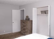 Thumbnail 13 of 17 - A bedroom with a bed, dresser, and open closet.
