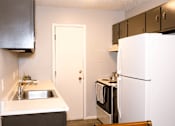 Thumbnail 1 of 17 - A kitchen with a sink, refrigerator, and cabinets.
